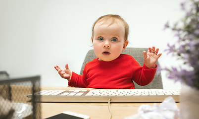 Image showing Happy child baby girl toddler sitting with keyboard of computer isolated on a white background