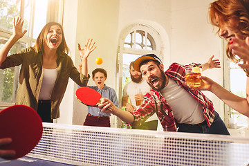 Image showing Group of happy young friends playing ping pong table tennis