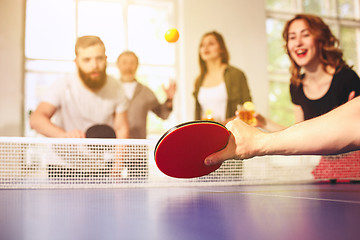 Image showing Group of happy young friends playing ping pong table tennis