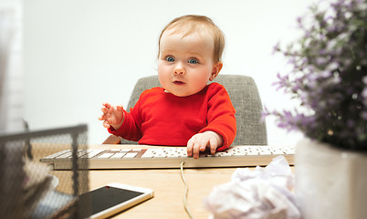 Image showing Happy child baby girl toddler sitting with keyboard of computer isolated on a white background