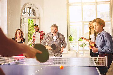 Image showing Group of happy young friends playing ping pong table tennis