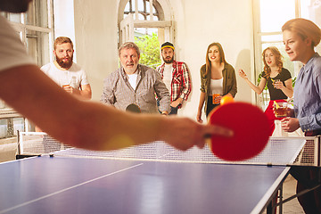 Image showing Group of happy young friends playing ping pong table tennis