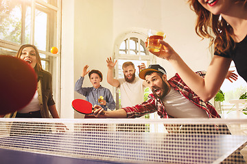 Image showing Group of happy young friends playing ping pong table tennis