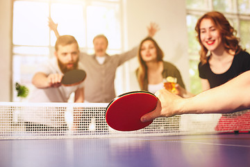 Image showing Group of happy young friends playing ping pong table tennis