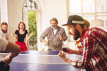 Image showing Group of happy young friends playing ping pong table tennis