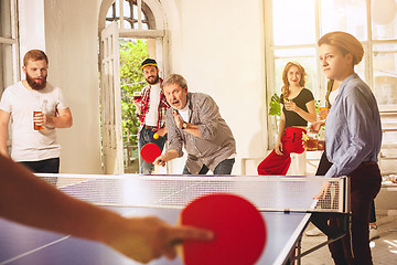 Image showing Group of happy young friends playing ping pong table tennis