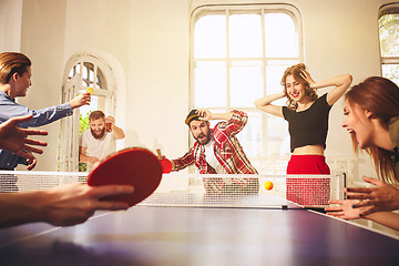Image showing Group of happy young friends playing ping pong table tennis