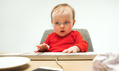 Image showing Happy child baby girl toddler sitting with keyboard of computer isolated on a white background