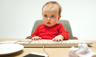 Image showing Happy child baby girl toddler sitting with keyboard of computer isolated on a white background