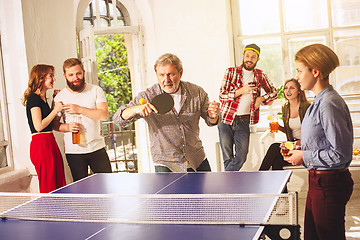 Image showing Group of happy young friends playing ping pong table tennis