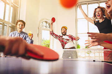 Image showing Group of happy young friends playing ping pong table tennis