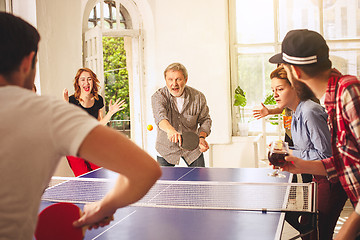 Image showing Group of happy young friends playing ping pong table tennis