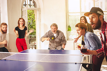 Image showing Group of happy young friends playing ping pong table tennis