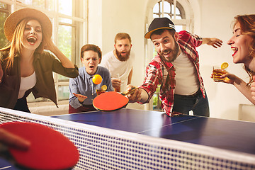 Image showing Group of happy young friends playing ping pong table tennis