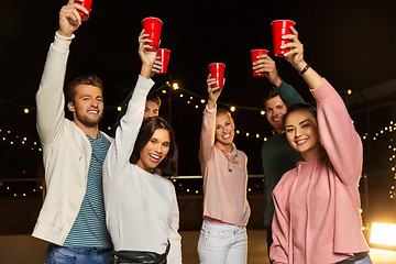 Image showing friends toasting party cups on rooftop at night