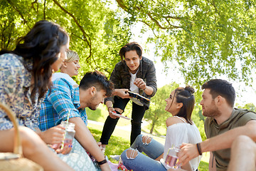 Image showing friends with drinks and food at picnic in park