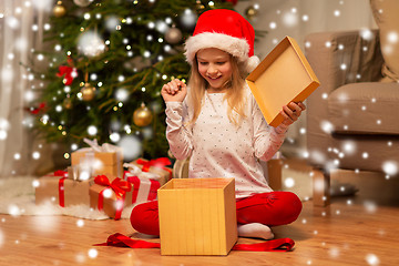 Image showing excited girl in santa hat opening christmas gift