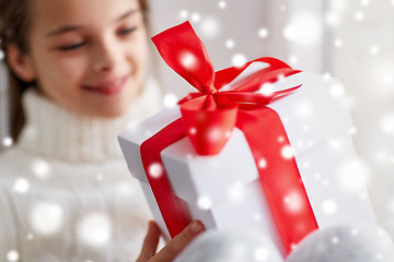 Image showing girl with christmas gift sitting on sill at home
