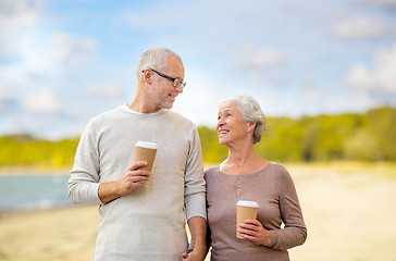 Image showing senior couple with takeaway coffee on beach