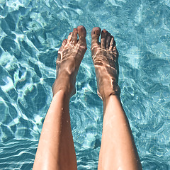 Image showing Female feet in turquoise water