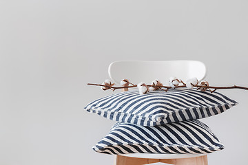 Image showing Striped cushions and cotton branch on a chair