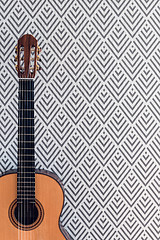 Image showing Classical guitar near a wall with geometric wallpaper