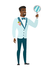 Image showing African-american groom holding hand mirror.