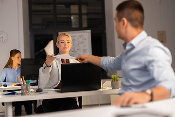 Image showing woman giving papers to colleague at night office