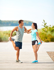 Image showing smiling couple stretching legs on beach