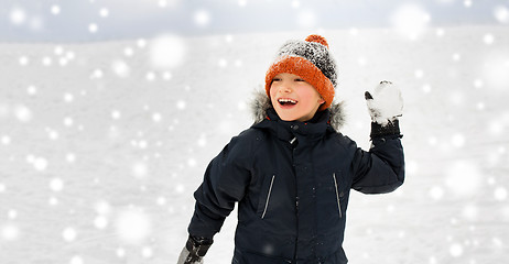 Image showing happy boy playing and throwing snowball in winter