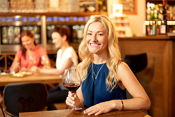 Image showing happy woman drinking red wine at bar or restaurant