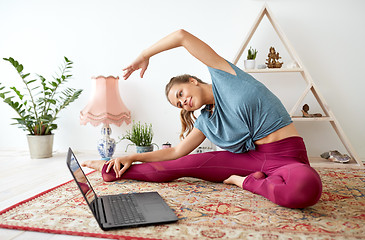 Image showing woman with laptop exercising at yoga studio