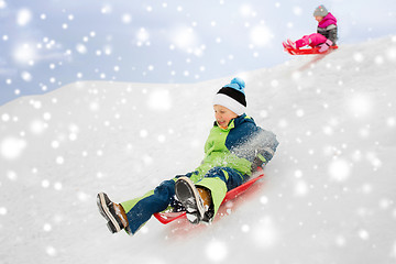 Image showing happy kids sliding on sleds down hill in winter