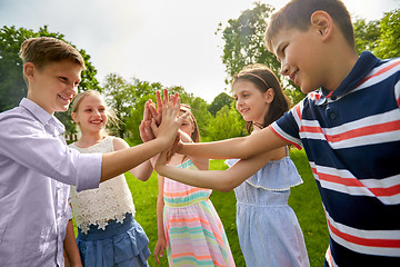 Image showing group of happy kids making high five outdoors