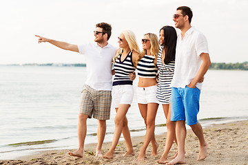 Image showing friends in striped clothes walking along beach