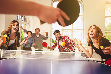 Image showing Group of happy young friends playing ping pong table tennis