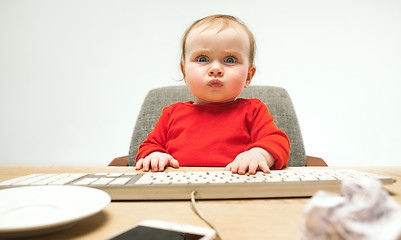 Image showing Happy child baby girl toddler sitting with keyboard of computer isolated on a white background