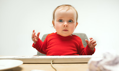 Image showing Happy child baby girl toddler sitting with keyboard of computer isolated on a white background