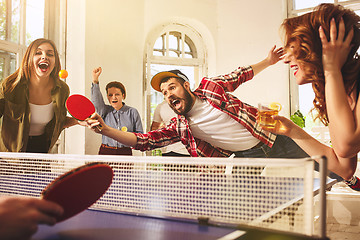 Image showing Group of happy young friends playing ping pong table tennis