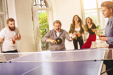 Image showing Group of happy young friends playing ping pong table tennis