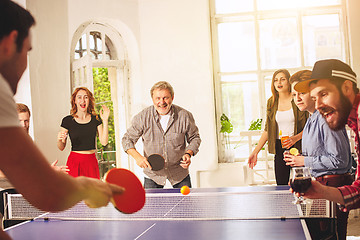 Image showing Group of happy young friends playing ping pong table tennis