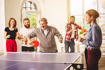 Image showing Group of happy young friends playing ping pong table tennis