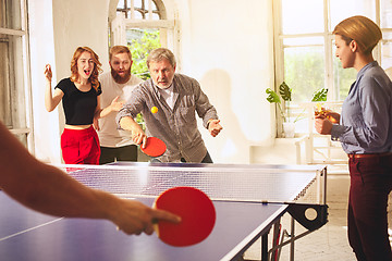 Image showing Group of happy young friends playing ping pong table tennis