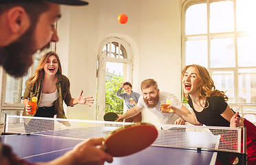 Image showing Group of happy young friends playing ping pong table tennis