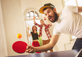 Image showing Group of happy young friends playing ping pong table tennis