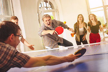 Image showing Group of happy young friends playing ping pong table tennis