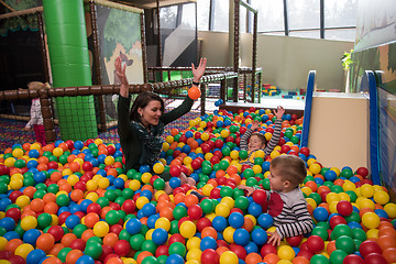 Image showing Young mom with her kids in a children\'s playroom