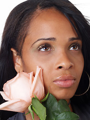 Image showing Young black woman with pink rose along cheek