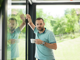 Image showing young man drinking morning coffee by the window