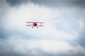 Image showing Vintage red propeller plane flying on a blue sky